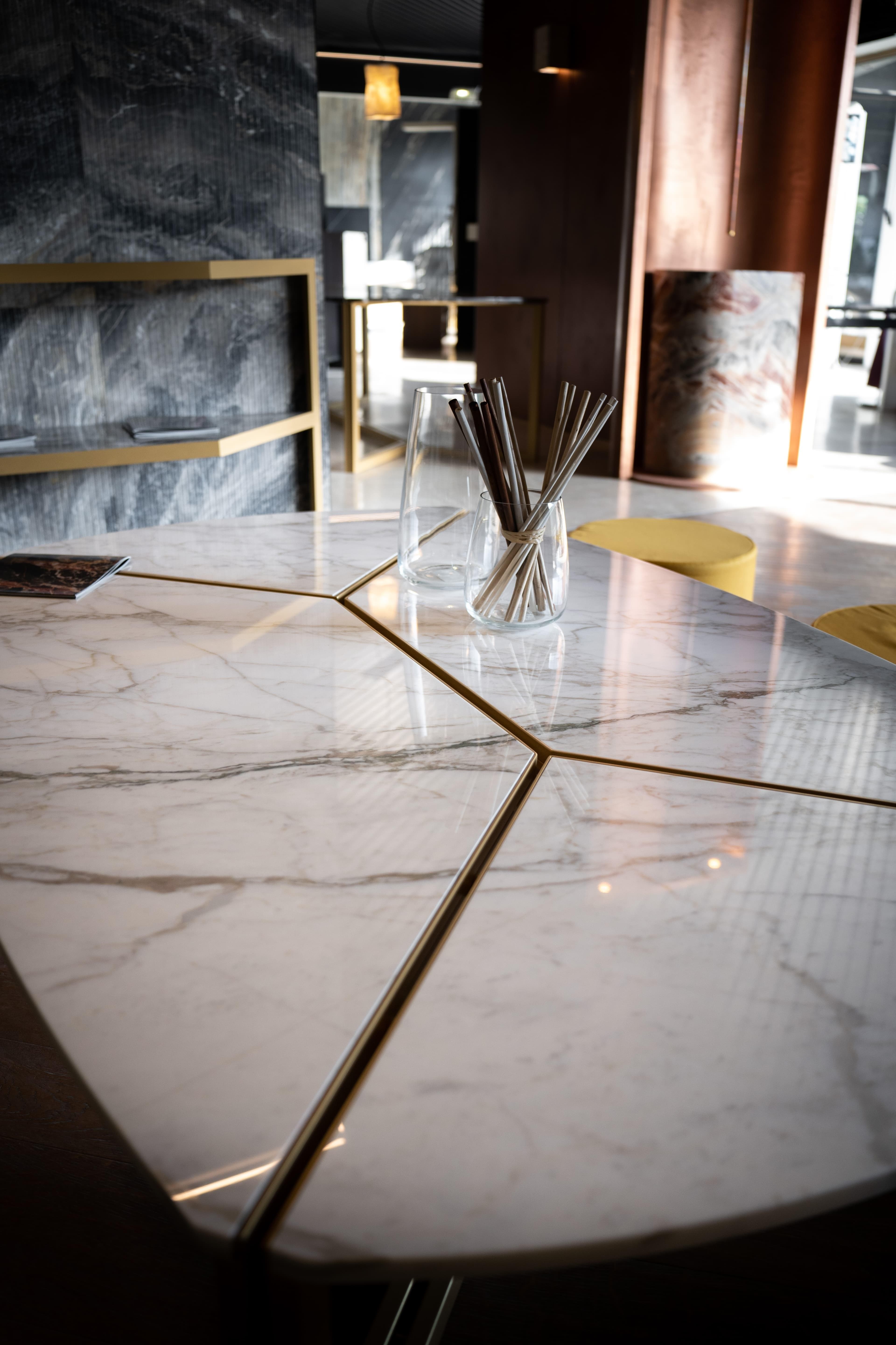Mesa de mármore com marchetaria em bronze e peças de vidro, em interior contemporâneo